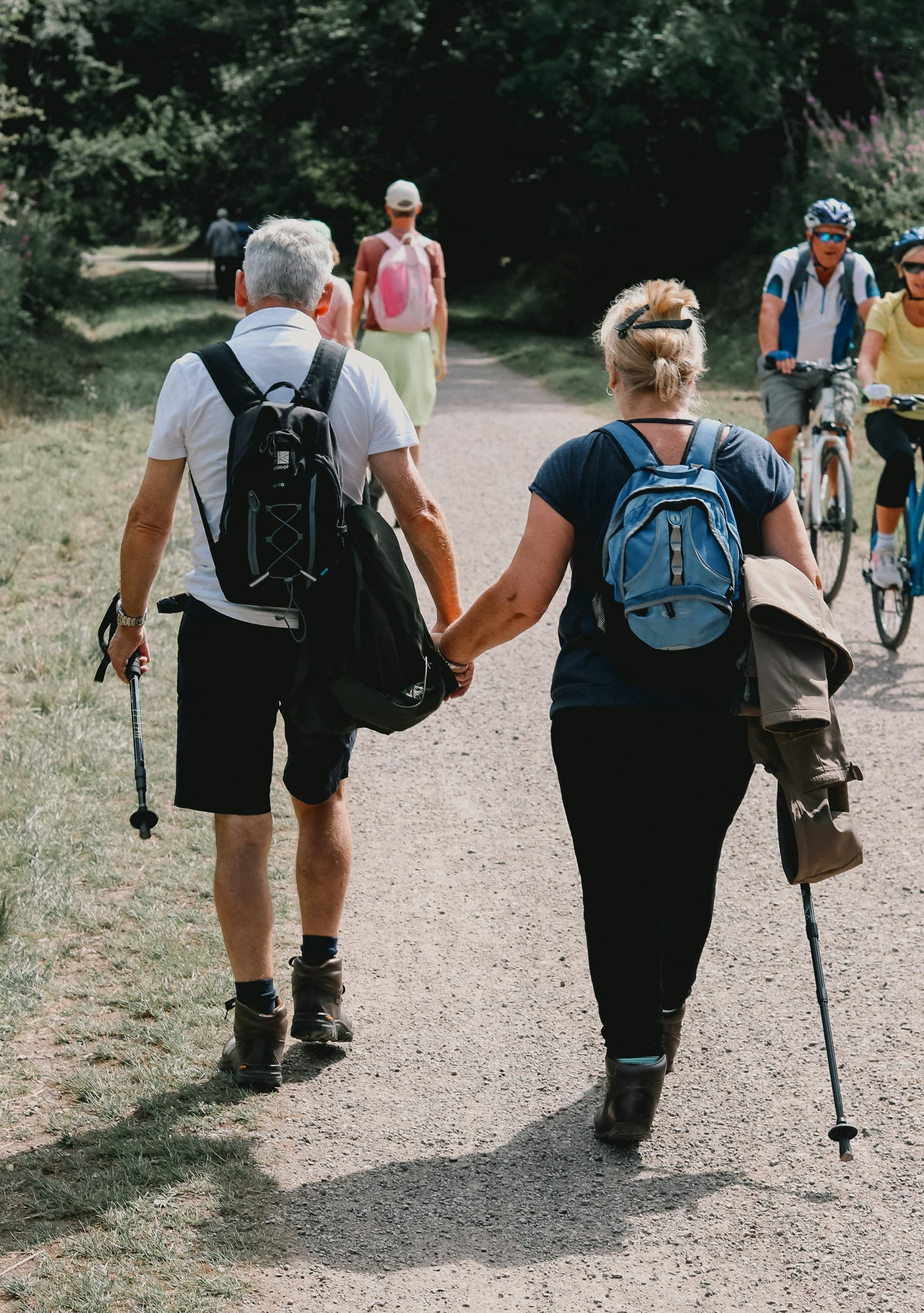 A couple holding hands as they walk along a woodland path